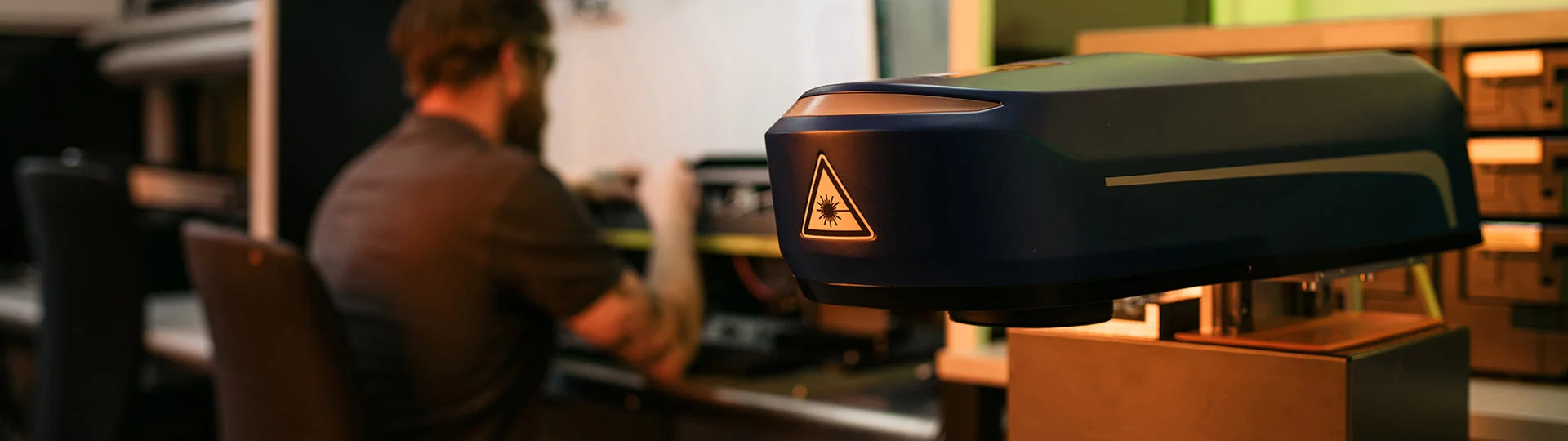 ACI Laser support team in the laboratory: employees in the background, laser head in the foreground