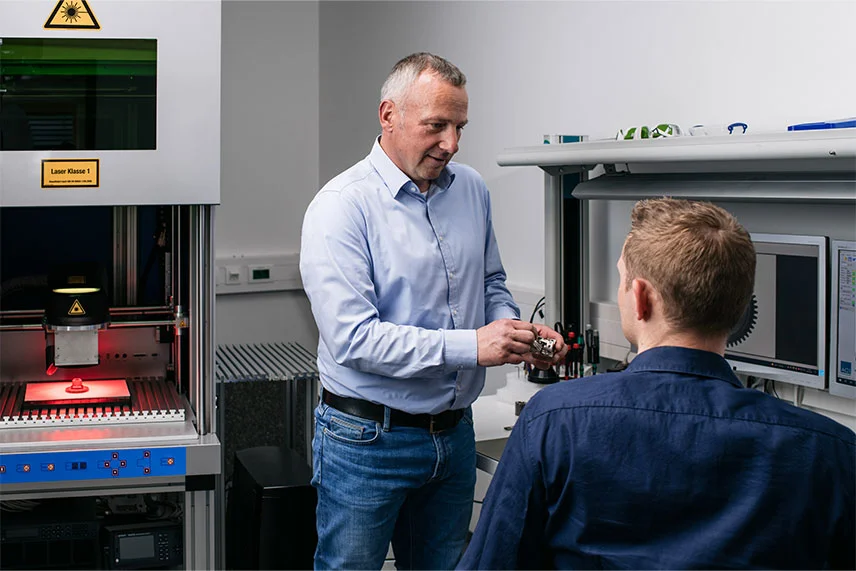 Two ACI employees discuss the discontinuation of a laser system for a customer.