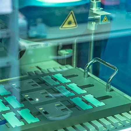 Blick durch Laserschutzglas auf Faserlaserkopf und Werkstückpalette