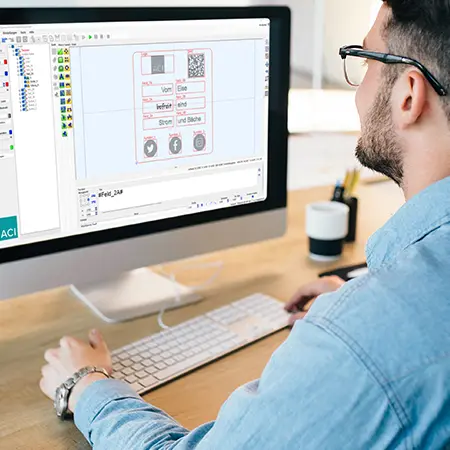 Man at desk, looking at the user interface of the Magic Mark laser software