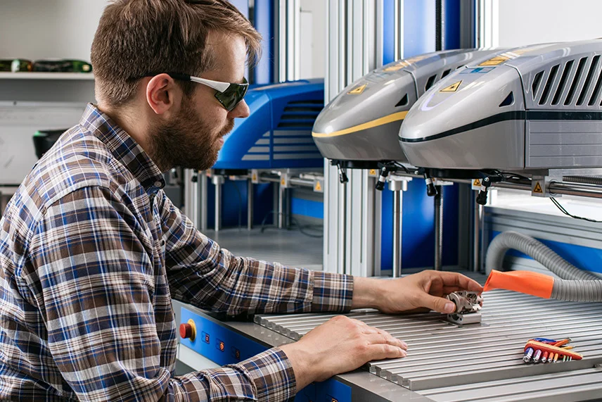 Application technician in the laboratory: start of sample part marking with material tests