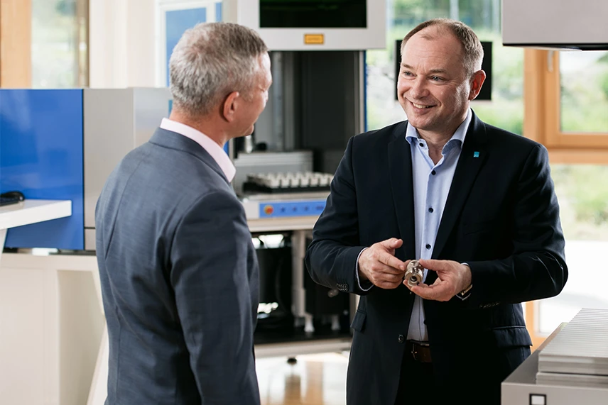 ACI Laser sales manager with customer and sample part, showroom in the background