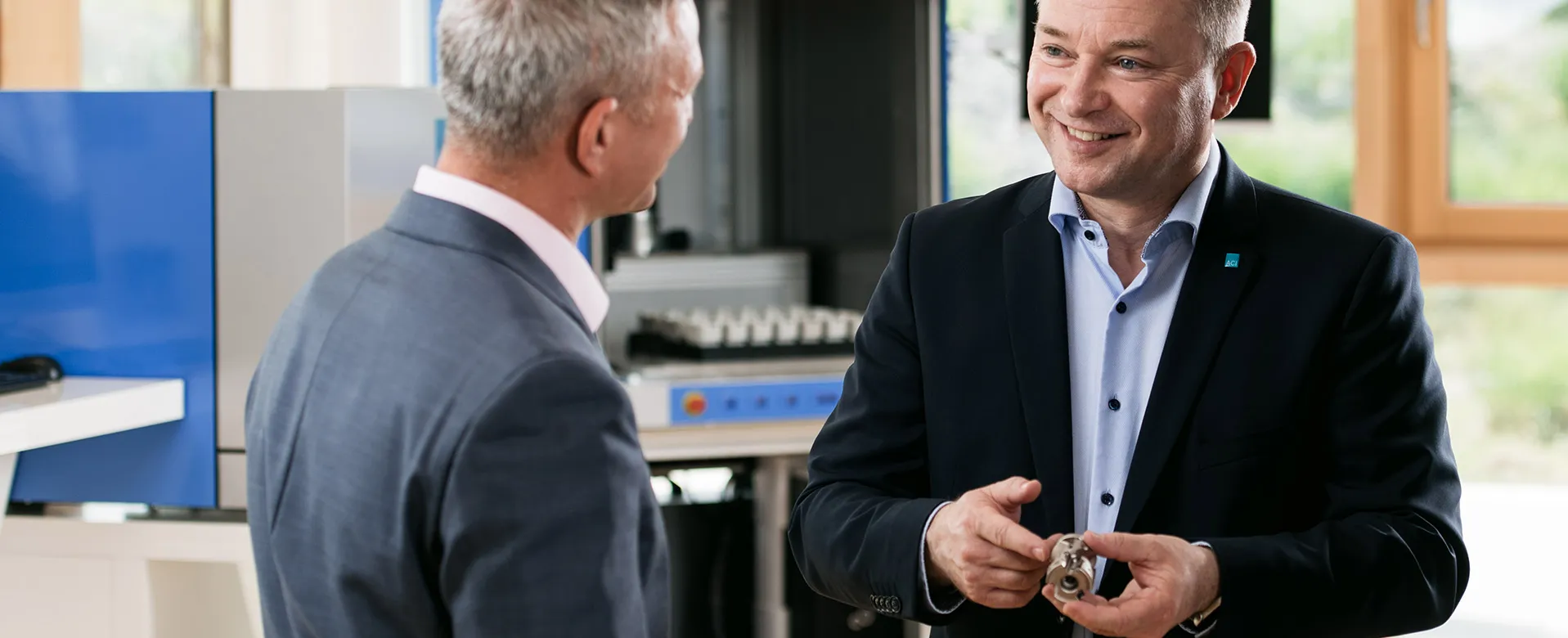 ACI Laser Vertriebsleiter mit Kunde und Musterteil, Showroom im Hintergrund