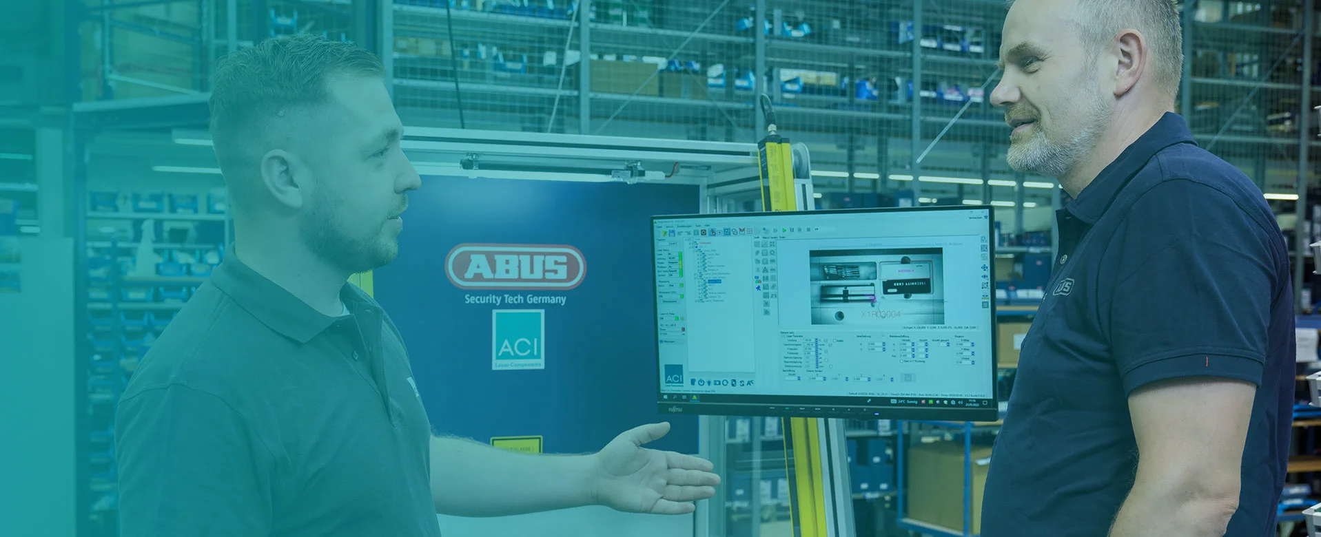 Two people in front of ACI laser system with Magic Mark software on monitor