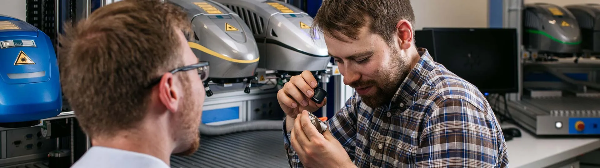 ACI Laser GmbH employees inspect a labeled sample part