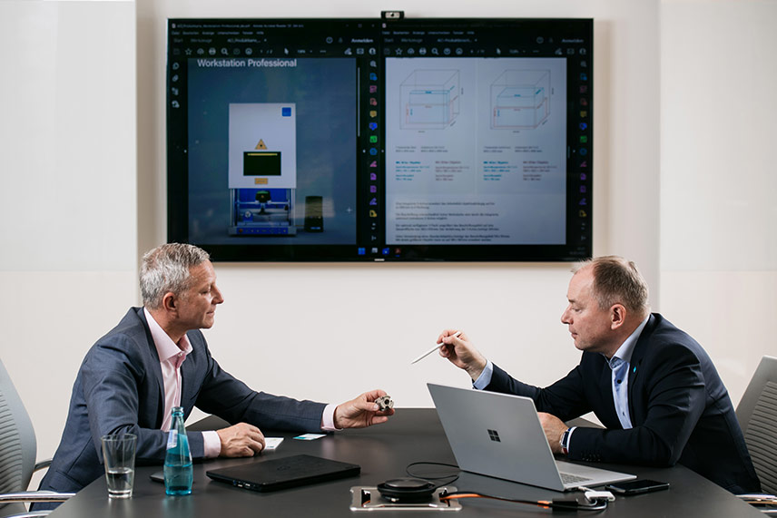 Zwei Personen im Fachgespräch bei ACI mit Produktdarstellung der Workstation am Bildschirm