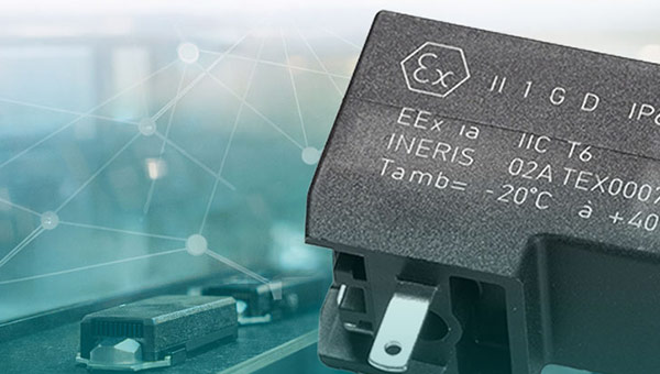 Close-up of a laser-marked connector/electronic component in the foreground against a blurred industrial background