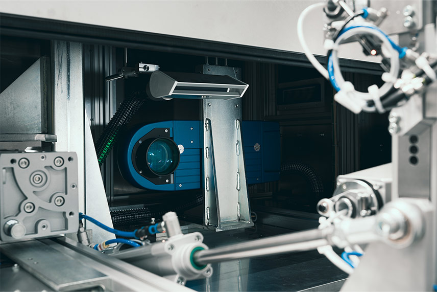 Laserkennzeichnungsmodul und Optik in einer integrierten Station mit Halterungen und Leitungen.